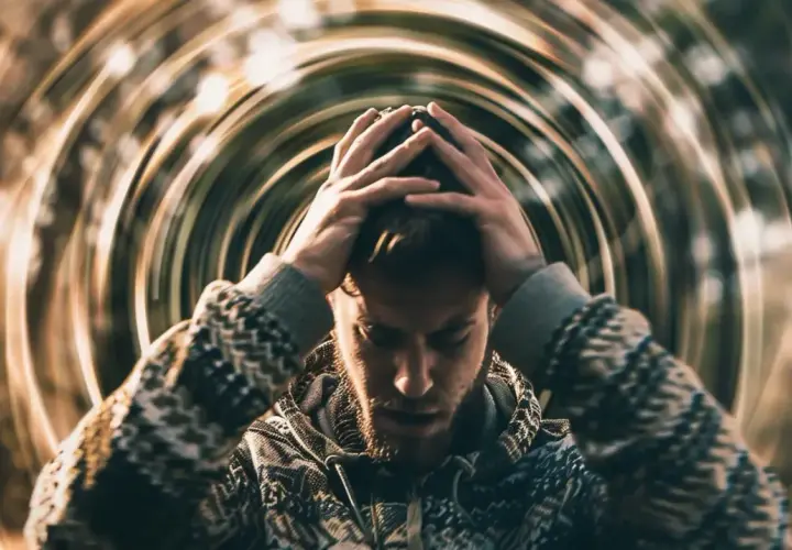 Mężczyzna z rękami na głowie, otoczony wirującymi liniami, symbolizującymi psychosomatykę i wewnętrzny niepokój.