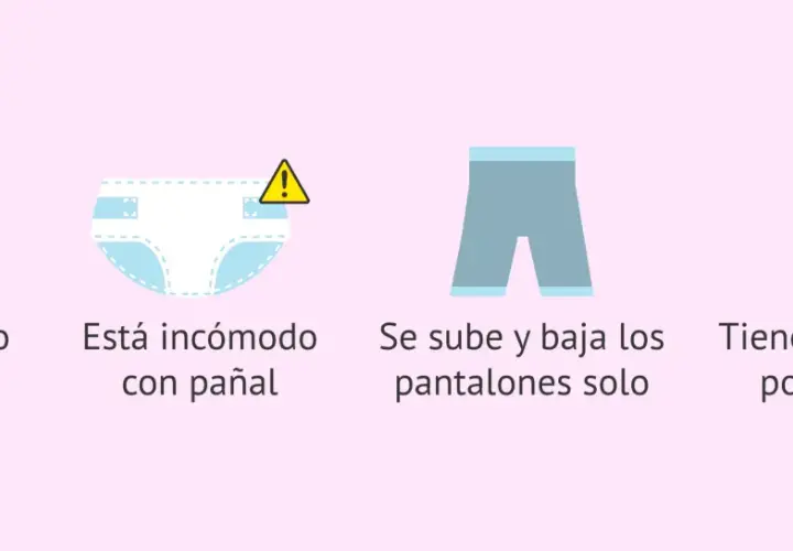 Bebé con pañal limpio, incómodo, bajándose pantalones y curioso por el baño. Señales para quitar el pañal.