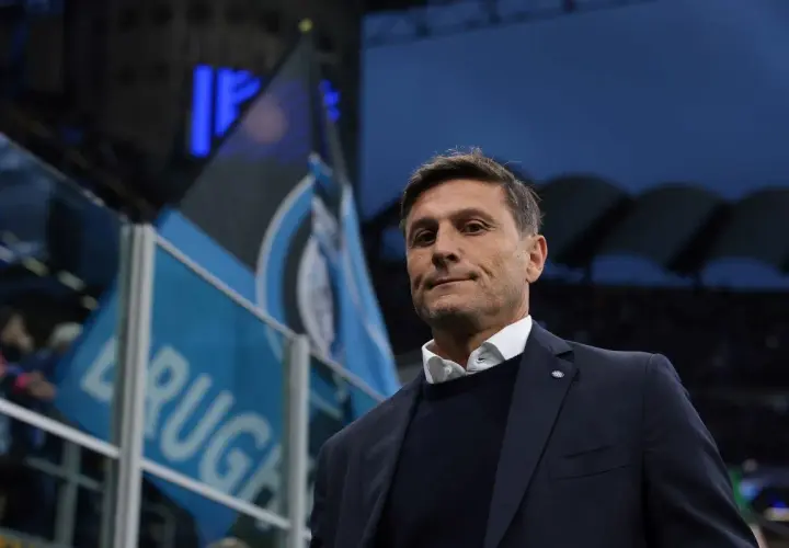 Trener piłkarzy z Mediolanu, z flagami Interu w tle, gotowy do meczu.