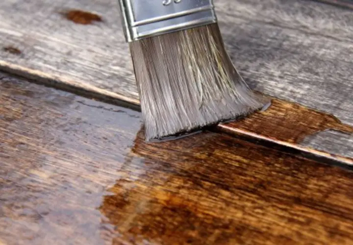 Pennello stende olio paglierino per legno su assi grezze, nutrendo e proteggendo la superficie.
