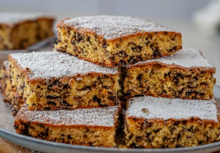 Stapel von saftigen Kuchenstücken mit Schokostückchen, bestäubt mit Puderzucker. Perfekt für einen schnellen Kuchengenuss.