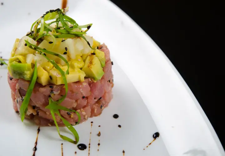 Deliziosa tartare di tonno con avocado e ananas, guarnita con erba cipollina e semi di sesamo nero.