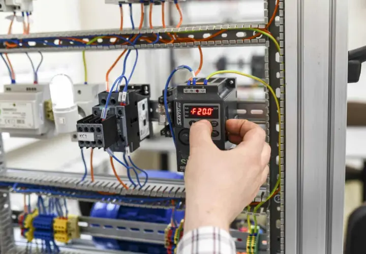 Ręka reguluje panel sterowania w szafie elektrycznej. Zastanawiasz się, ile zarabia magister inżynier elektryk?