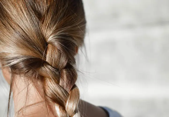 Närbild på en fläta med blont hår. Några små hårstrån som går av syns längs med flätan.