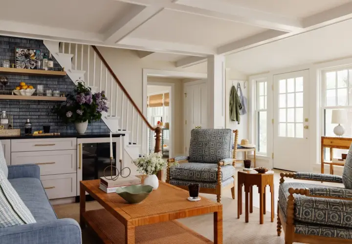 Cozy living room with blue sofa, patterned armchairs, and a rattan coffee table, offering charming farmhouse furniture ideas.