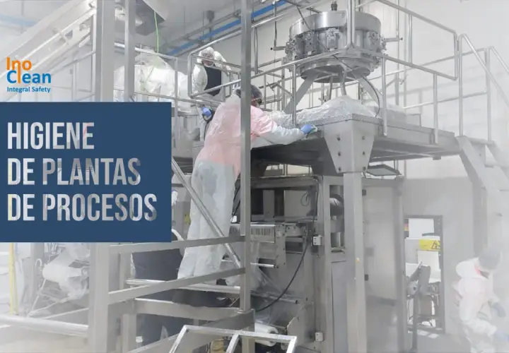 Trabajadores con trajes protectores limpian maquinaria industrial. La asepsia que es, se aplica para garantizar la higiene en plantas de procesos.