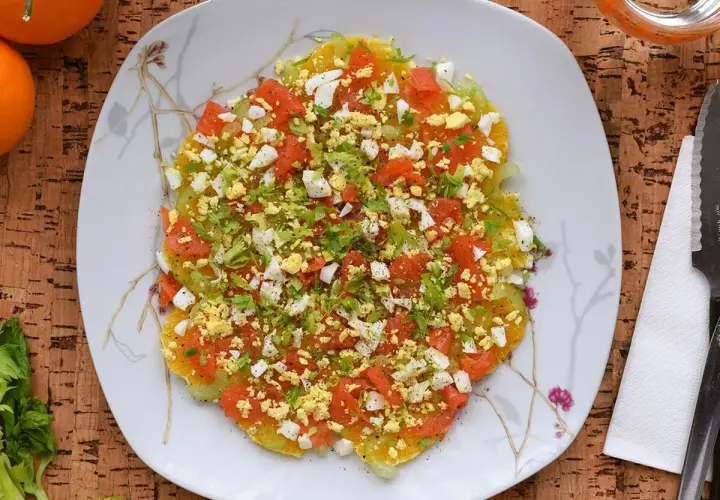 Deliciosa ensalada de invierno con rodajas de naranja, tomate picado, huevo duro y perejil fresco.