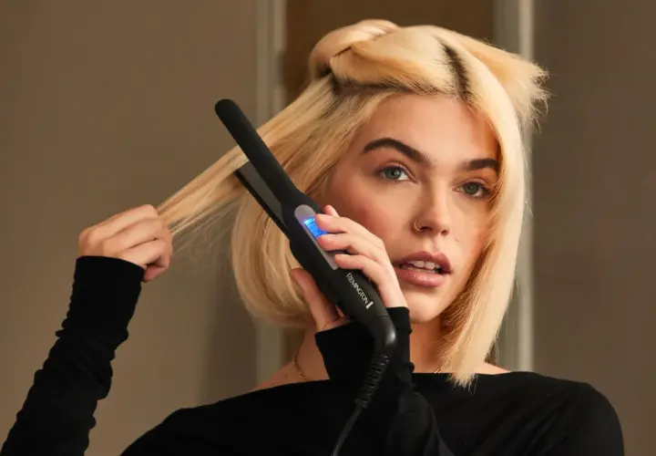 Blondynka używa prostownicy Remington, by nadać objętość włosom u nasady.