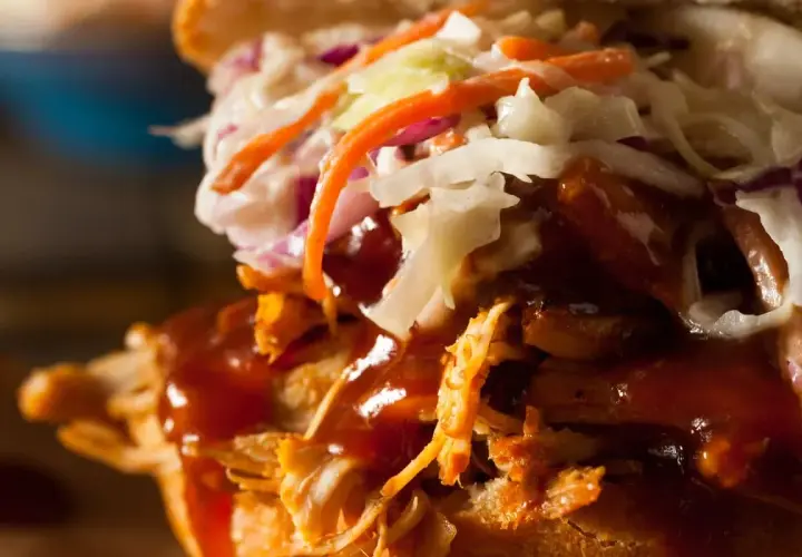 Gros plan sur un sandwich gourmand : effiloché de porc savoureux, sauce barbecue onctueuse et salade de chou croquante. Un délice !