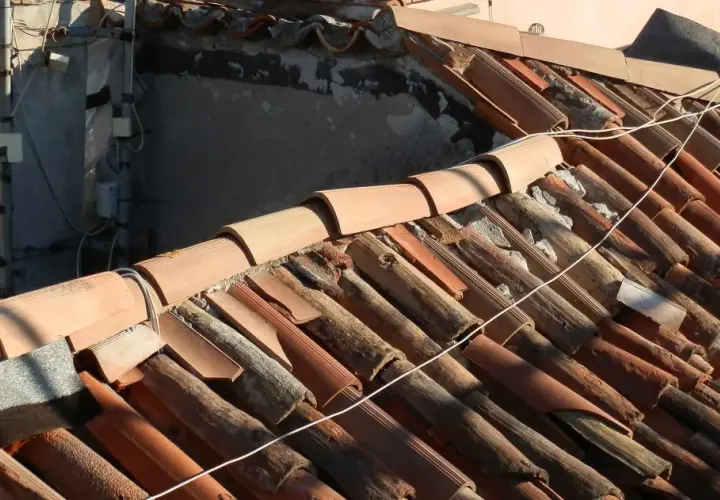 Dettaglio di un vecchio tetto con tegole in terracotta danneggiate, un esempio di come sistemare un vecchio tetto per ripristinarne l'integrità.