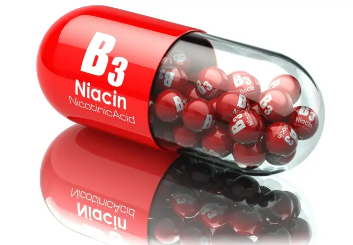 Czerwona kapsułka z witaminą B3 (niacyna) wypełniona małymi, czerwonymi kulkami z napisem "Niacin B3".