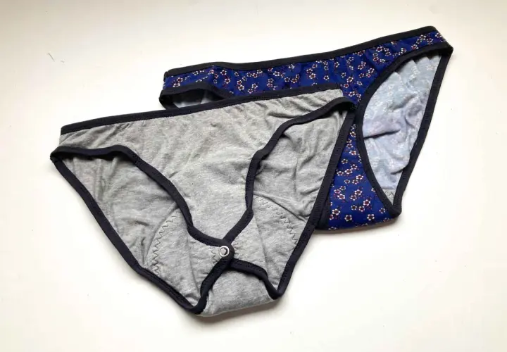 Two pairs of cotton underwear, one grey with a snap closure, the other blue floral. Perfect for a DIY period underwear project.