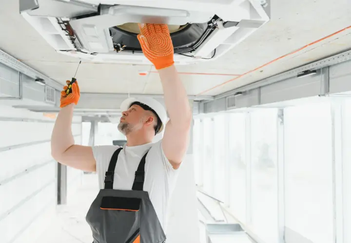 Técnico revisa unidad de aire acondicionado en el techo. Aprende como saber si un aire acondicionado tiene gas.