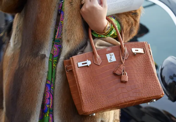 Elegancka torebka marki Hermes w kolorze koniaku, wykonana ze skóry krokodyla, z charakterystycznym zapięciem i małą kłódką.