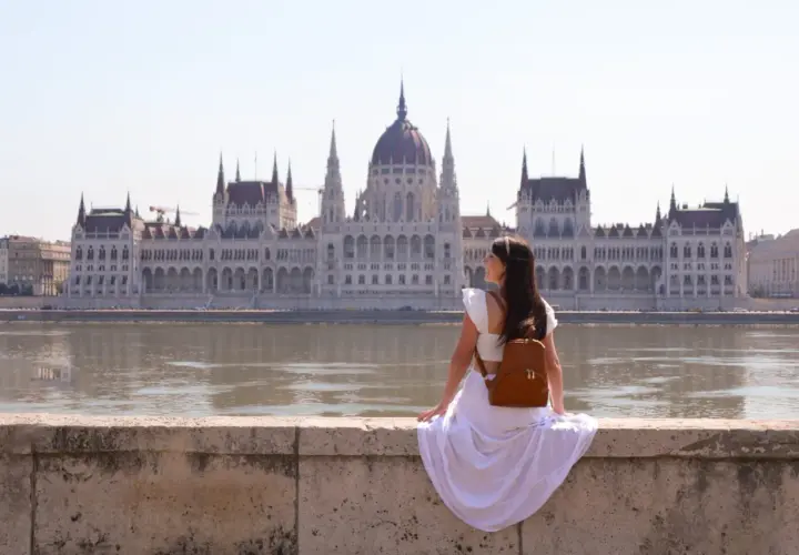 Mujer con mochila admira el Parlamento de Budapest, un lugar imprescindible que ver en Budapest.