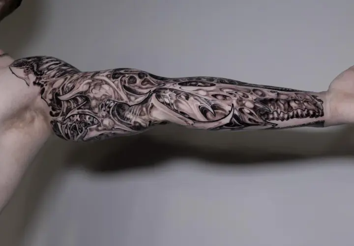 Imponujący greywash tattoo na ramieniu, przypominający mechaniczną protezę z ostrymi elementami i detalami.