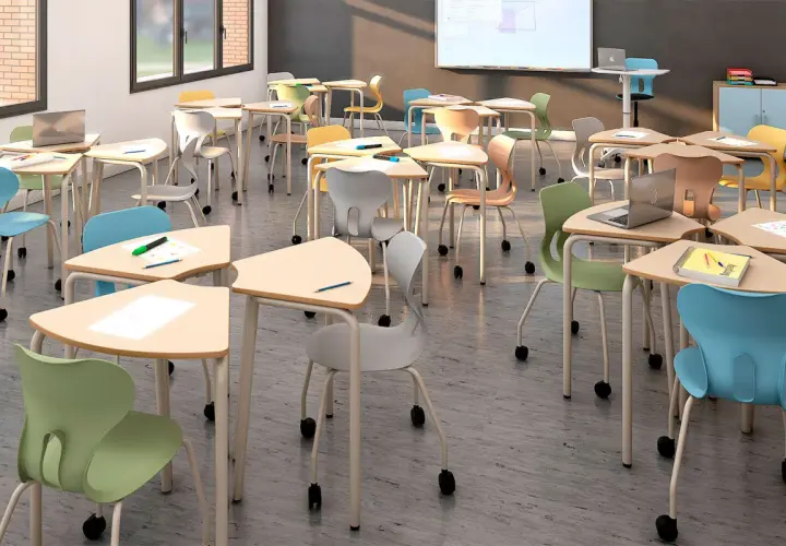 Aula moderna con mobiliario escolar innovador: mesas triangulares y sillas ergonómicas de colores vibrantes, listas para el aprendizaje.