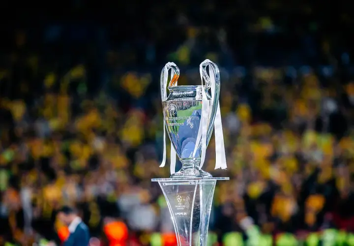 Trofeum Ligi Mistrzów na tle rozmazanej publiczności. Wartość awansu do Ligi Mistrzów jest ogromna.
