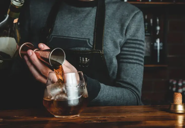 Barman nalewa whisky Glenlivet 12 do szklanki z lodem. Wiele pozytywnych opinii potwierdza jej jakość.