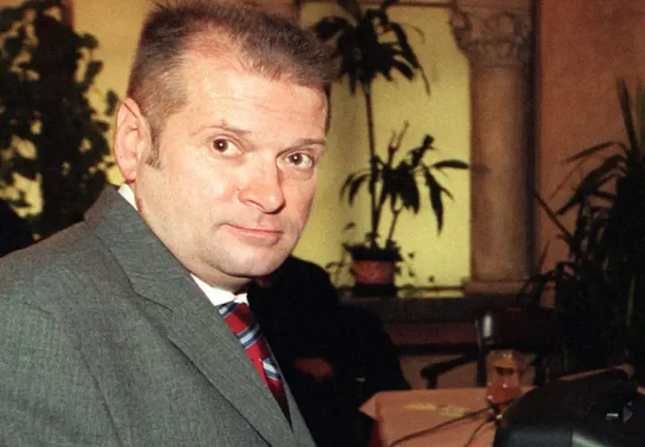 Krzysztof Rutkowski młody, w szarym garniturze i czerwono-niebieskim krawacie, patrzy w obiektyw.