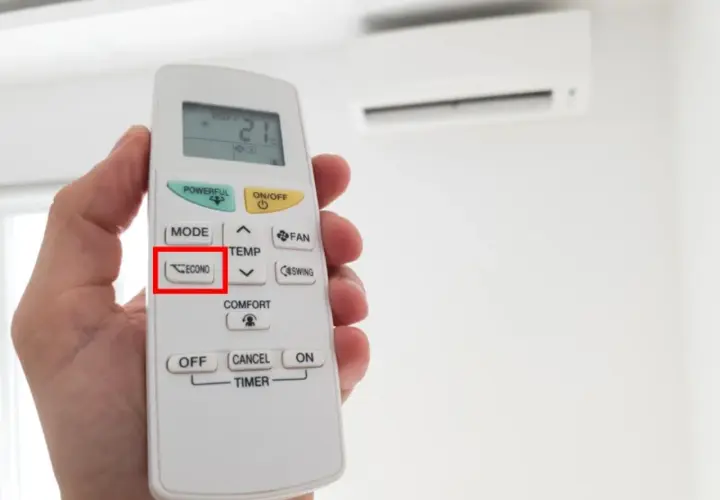 Mano sosteniendo un control remoto de aire acondicionado, con el botón "ECONO" resaltado. Activa el modo eco para ahorrar energía.