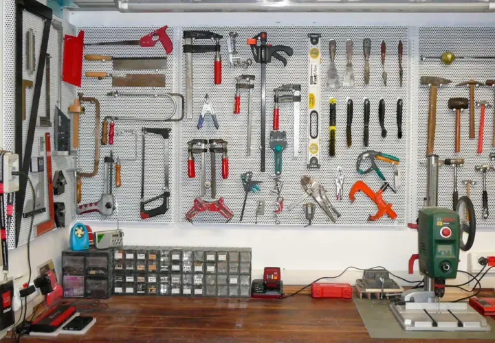 Parete porta attrezzi con pallet, organizzata con martelli, seghe, pinze e altri strumenti.