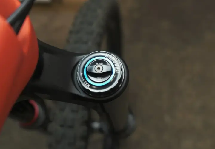 Close-up of an orange MTB frame and black suspension fork with a "Charger" damper adjustment knob, part of the mtb suspension setup.