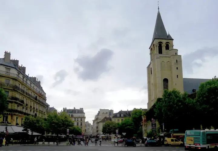 Wieża kościoła Saint-Germain-des-Prés na tle paryskiej ulicy z budynkami i przechodniami.