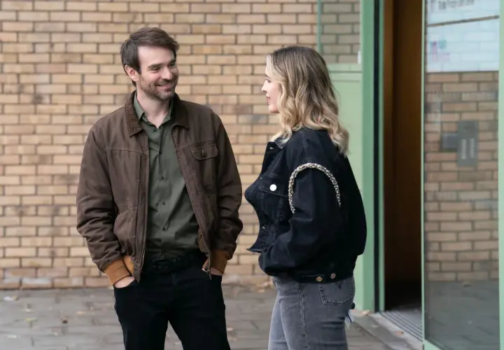 Man och kvinna pratar utanför en byggnad, kanske en scen från en svensk kin serie.