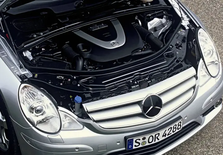 Motor de Mercedes Clase R, con capó abierto. Se aprecian componentes mecánicos y el logo de Mercedes. Posibles mercedes clase r problemas.