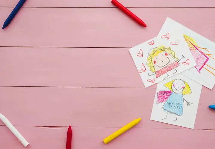 Dziecięce rysunki i kredki na różowym tle. Może to być ilustracja do sprawy o pozew o alimenty na dwoje dzieci.