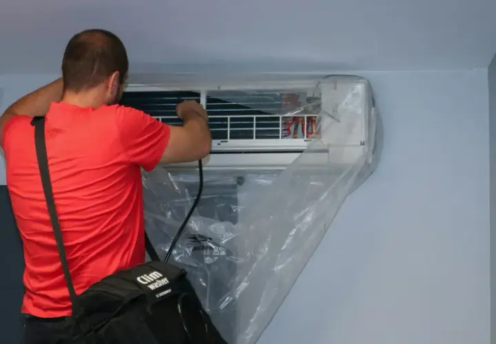 Un technicien effectue l'entretien d'une climatisation murale, une tâche essentielle pour tout locataire ou propriétaire soucieux de son confort.