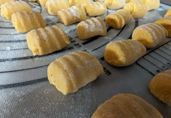 Gnocchi de patate douce faits maison, prêts à être cuits, saupoudrés de farine sur une planche.