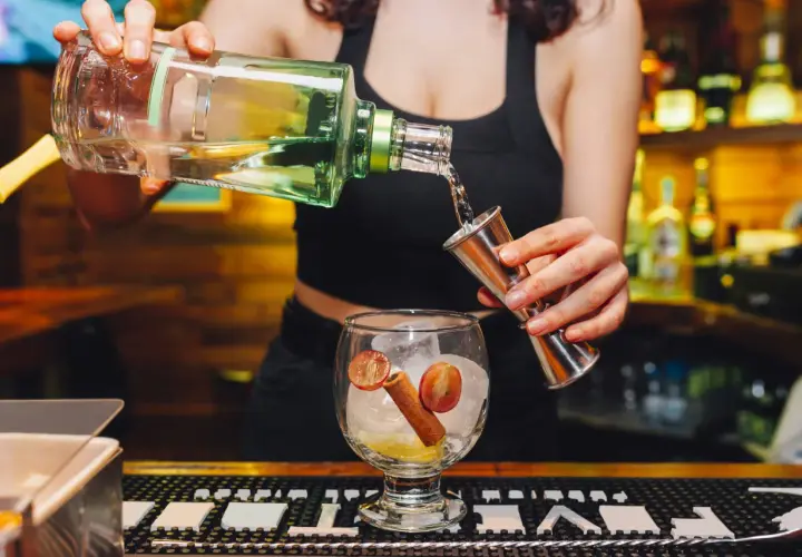 Barmanka nalewa alkohol do kieliszka z lodem, cytryną i cynamonem. Zastanawiasz się, ile zarabia barmanka?