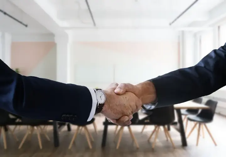 Two men in suits shake hands, a gesture of how to be professional with coworkers.