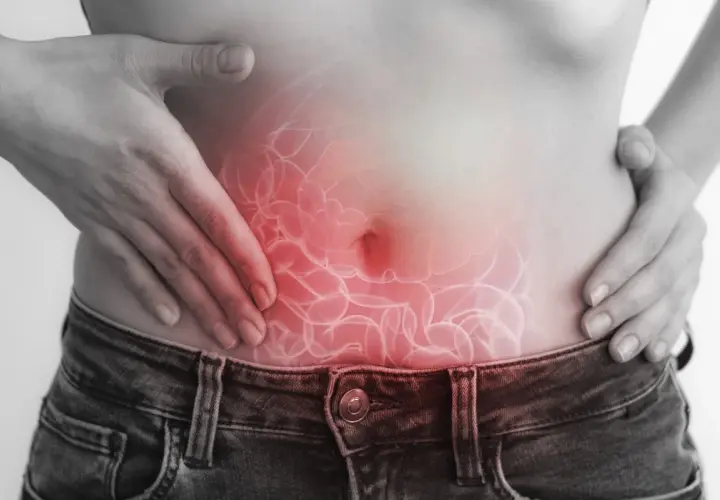 Dolore addominale, forse legato a escherichia coli in gravidanza. Mani sulla pancia con un'illustrazione degli intestini infiammati.