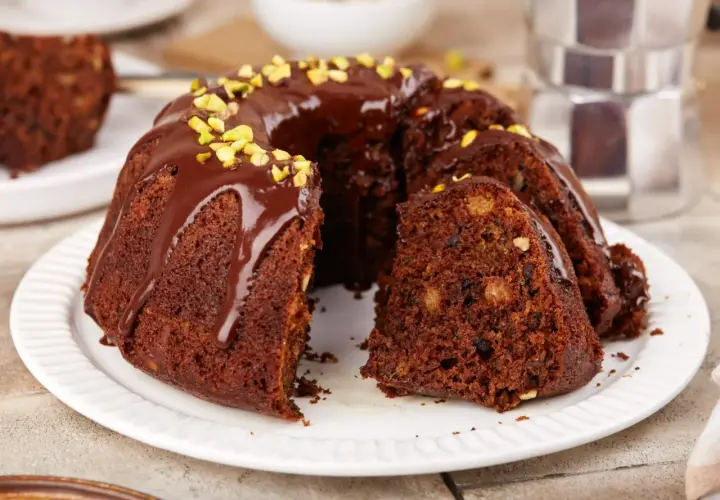 Pyszna babka na oleju, polana czekoladą i posypana pistacjami, czeka na kawę.