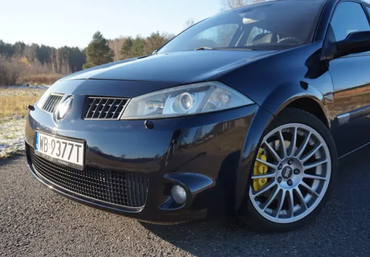 Ciemnoniebieski Renault Megane 2 z żółtymi zaciskami hamulcowymi Brembo na alufelgach.