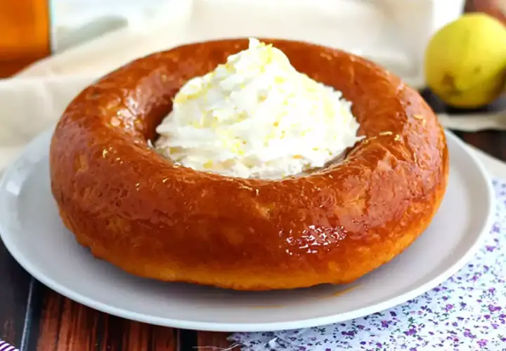 En gyllene baba, en klassisk dessert, toppas med fluffig grädde och citronskal. Perfekt för en fika!
