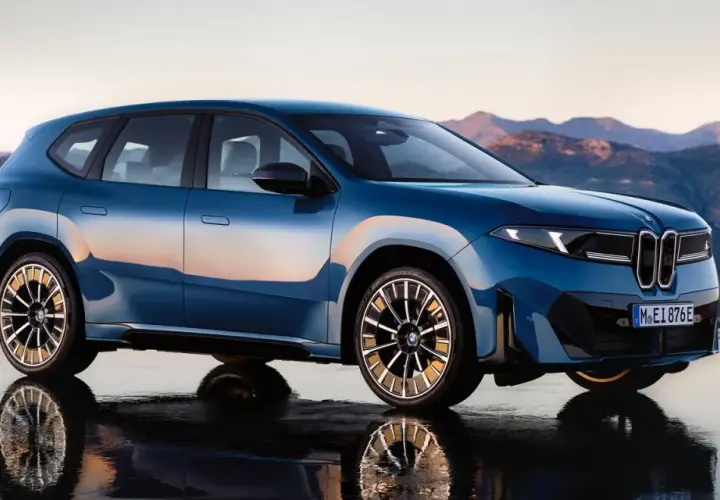 La BMW Neue Klasse blu metallizzato, con riflessi del tramonto, si staglia su uno sfondo montuoso.