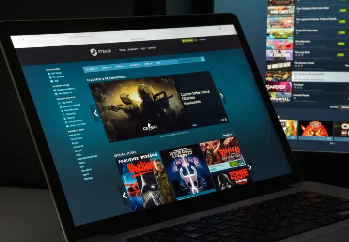 Ekran laptopa z witryną Steam, pokazujący jak działa udostępnianie gier. Widoczne gry i oferty specjalne.