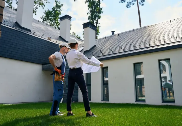 Architekt i budowlaniec omawiają plany domu. Czy można mieszkać w domu bez odbioru? To pytanie, na które odpowiedź znajdą analizując projekt.