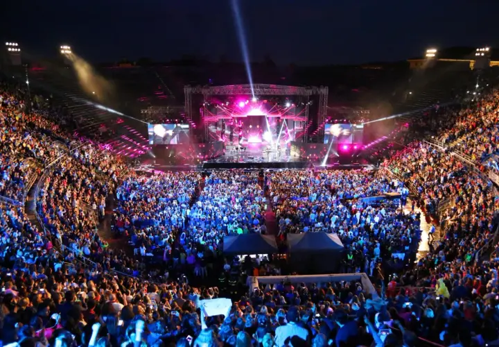 Koncert włoskich piosenkarzy na wypełnionym po brzegi stadionie. Tłum w euforii, światła sceny i ekranów tworzą magiczną atmosferę.
