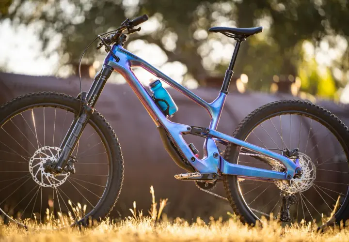 A stunning 2018 Cannondale Jekyll mountain bike with a iridescent blue frame, parked in golden hour light.