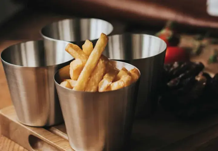 Tre metallbägare med hemmagjorda pommes frites. En bägare är fylld med gyllene pommes.