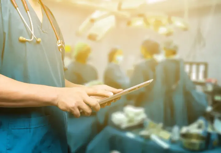 Medico con stetoscopio e tablet in sala operatoria. In caso di errori medici a chi rivolgersi per assistenza.