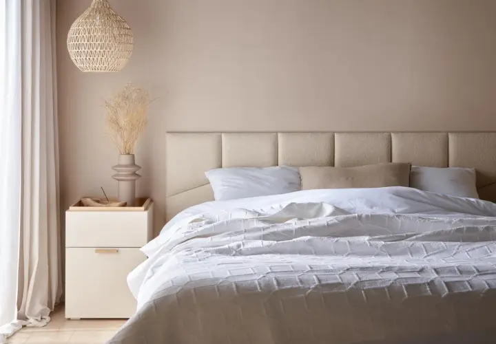Miękkie, tapicerowane panele tworzą elegancki **pomysł na zagłówek do łóżka**. Jasna kolorystyka i minimalistyczny design.