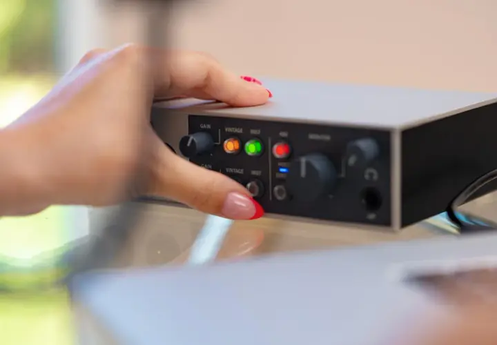 Dłoń z paznokciami ustawia pokrętło na interfejsie audio. Dowiedz się, jak podłączyć mio smartbox iii.