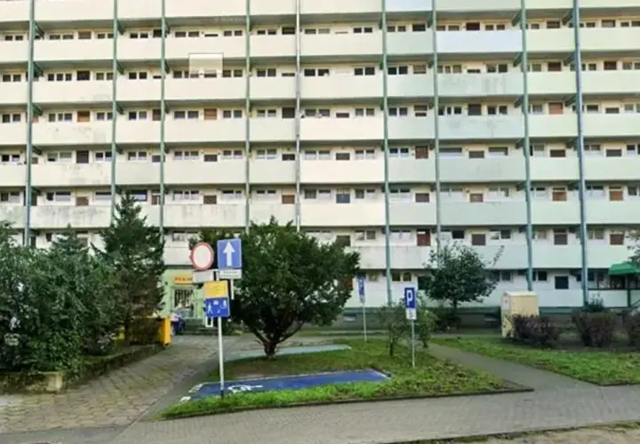 Wyznaczono miejsce dla niepełnosprawnych bez koperty, obok zieleni i bloków mieszkalnych.