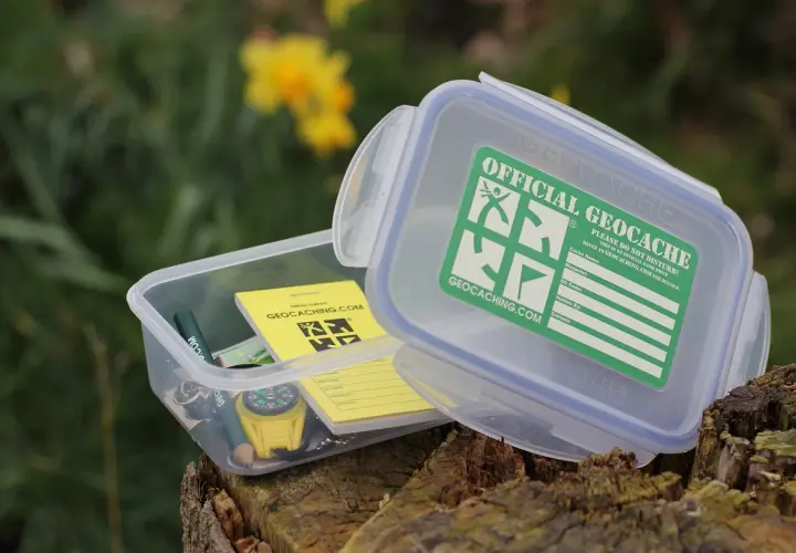 Pudełko z napisem "Official Geocache" i kompasem. To jest właśnie geocaching – zabawa w poszukiwanie skarbów.